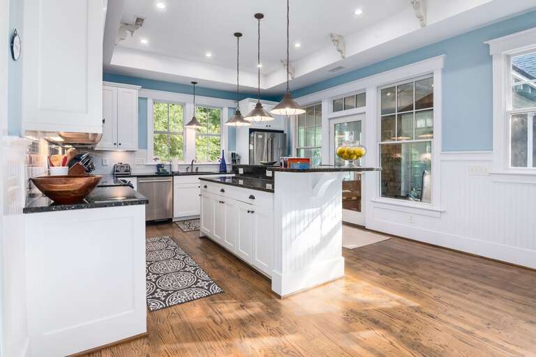 Bright, Blue-bordered Vacation Rental Kitchen With Wooden Flooring And Hanging Lights Bright, Blue-bordered Vacation Rental Kitchen With Wooden Flooring And Hanging Lights