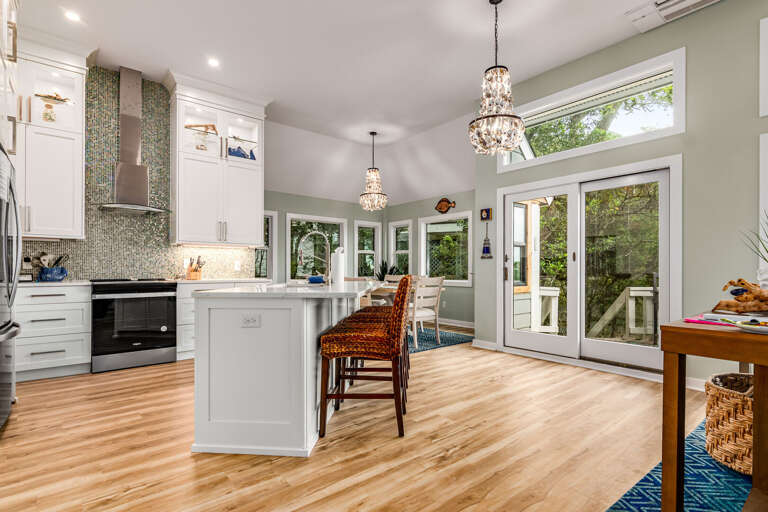 Spacious Kitchen With Island, Hardwood Floors, Hanging Lights, And Sliding Doors Leading Outside