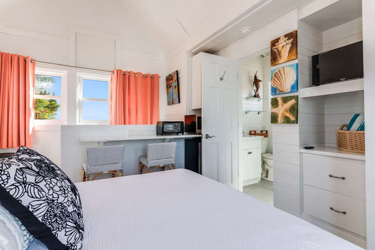 Bright Bedroom With Blue And Coral Curtains, White Walls, And Built-in Shelves