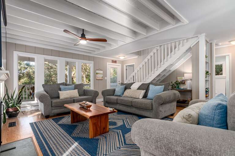 Living Space With Sofas, Striped Rug, Staircase, And Ceiling Fan