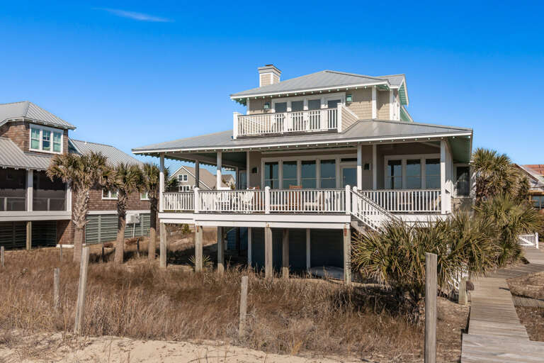 Seaside Structure Standing By Sandy Shores, Surrounded By Slender Grass