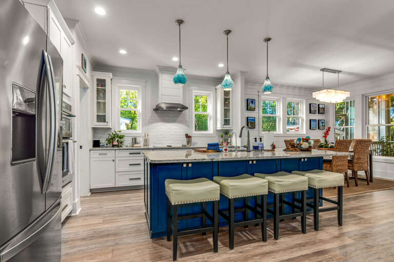 Bright, Spacious Kitchen With Blue Bar Stools And White Cabinets In A Vacation Rental