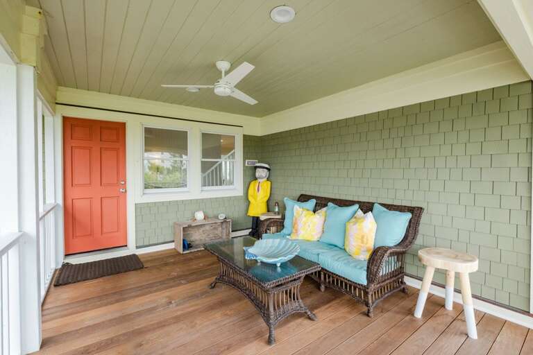 Vacation Rental Veranda With Vibrant Pillows, Rustic Bench, And Red Door