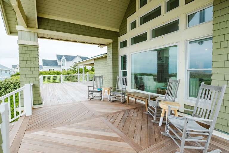 Porch With Rocking Chairs, Paneled Glass Windows, And Patterned Wooden Floor