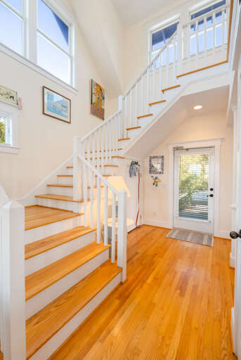 Brightly Lit Indoor Entryway Showcasing A Stairway And Wooden Floors