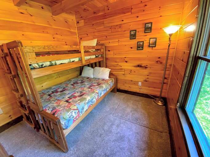 Bunk bedroom, featuring a twin over full bed with view of the seasonal stream and small pond behind the cabin