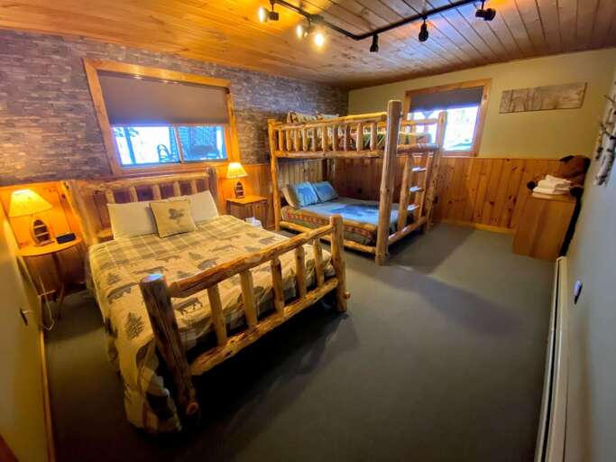 Downstairs, you will find 2 bedrooms and 1 bathroom. One of the 2 bedrooms features 3 queen beds - one in bunk format, one standard. Rustic wood ceiling and faux stone wall add to the ambience!