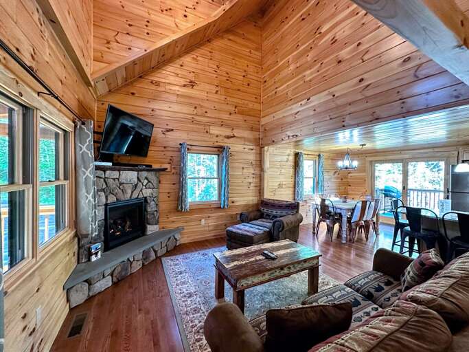 The modern open-concept living area with a gas fireplace featuring a flat-screen TV with a surround sound bar.