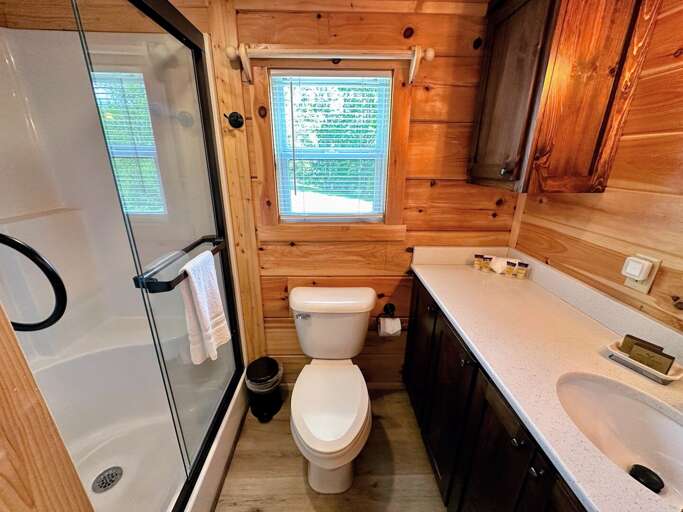 A comfortably spaced three-quarter bathroom (sink, toilet and shower) with towels.