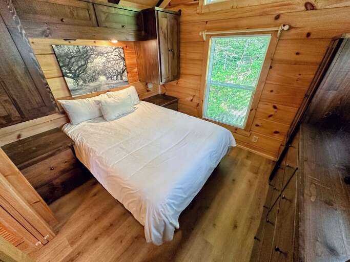 Topline tiny home has a queen sized bedroom. This shows a few of the eighteen storage behind and on the side of the bed.