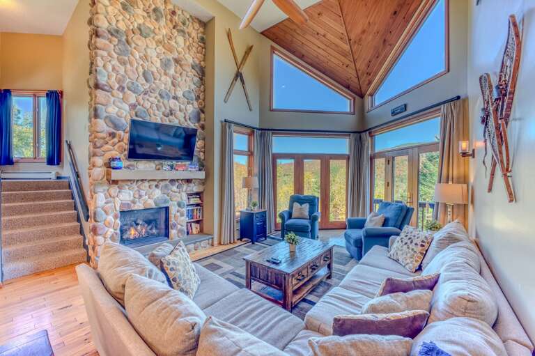 Inside it offers an open-concept living, dining, and kitchen area featuring vaulted ceilings, large TV, and a stunning stone fireplace.