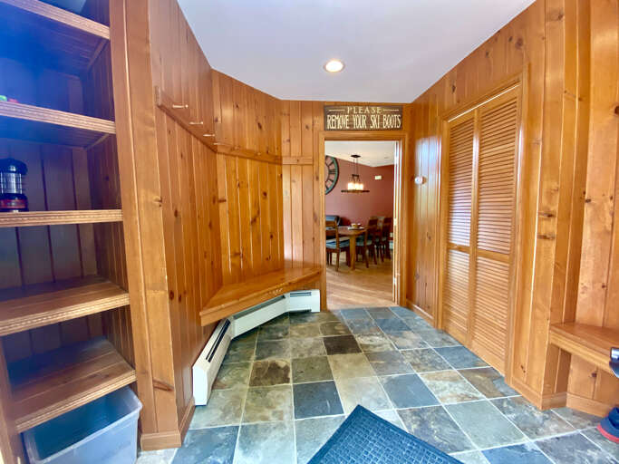 Interior Entryway With Wooden Walls And Tiled Floor Leading To Dining Area