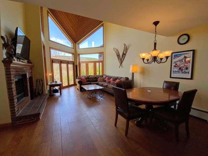Dining/Living Area: Open concept space with a round dining table that seats 4 and comfortable furniture surrounding the wood burning fireplace. Has access to the back deck and Mt. Washington views.