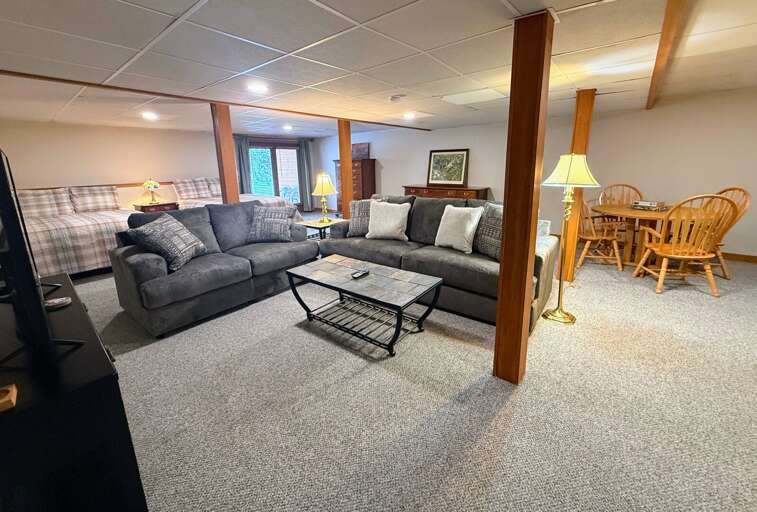 Plush Gray Sofa, Glass Table, Wooden Chairs, Window-lit Living Space