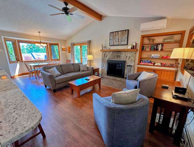 The living room is outfitted with a wood burning fireplace, TV and AC adjacent to a convenient breakfast bar and dining table