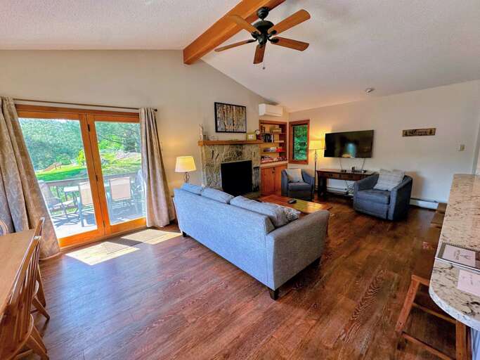 The living room is outfitted with a wood burning fireplace, TV and AC adjacent to a convenient breakfast bar and dining table