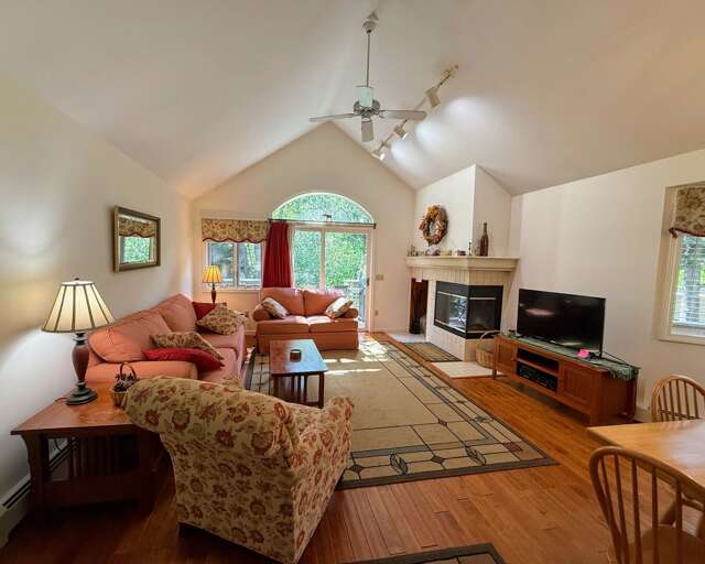 A sunny open concept space with dining table that seats 6 and comfortable furniture that surrounds the fireplace.