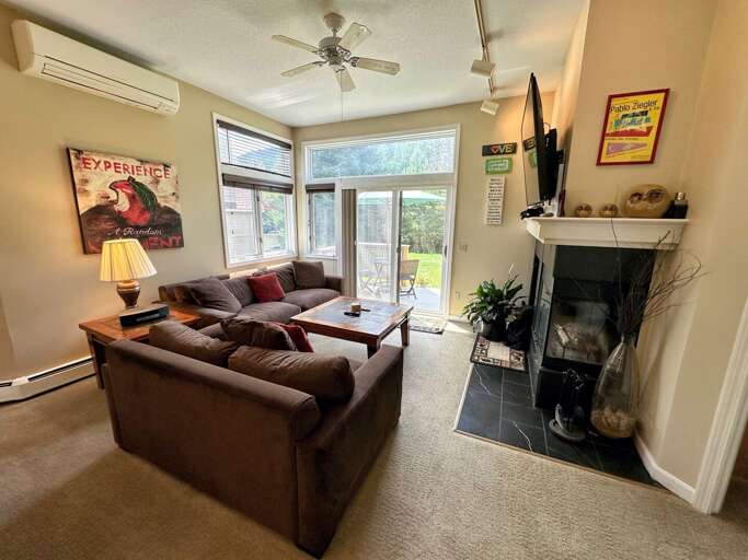 Comfortable furniture that surrounds a wood burning fireplace with access to the back deck.