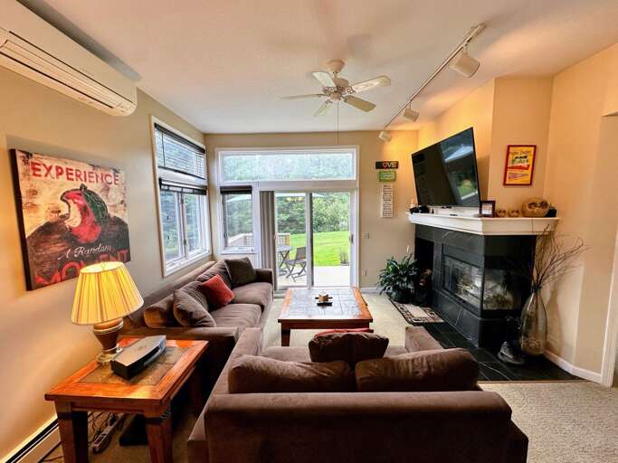 Living Room With Sofa, Fireplace, And Television, Framed By Forest-facing Windows