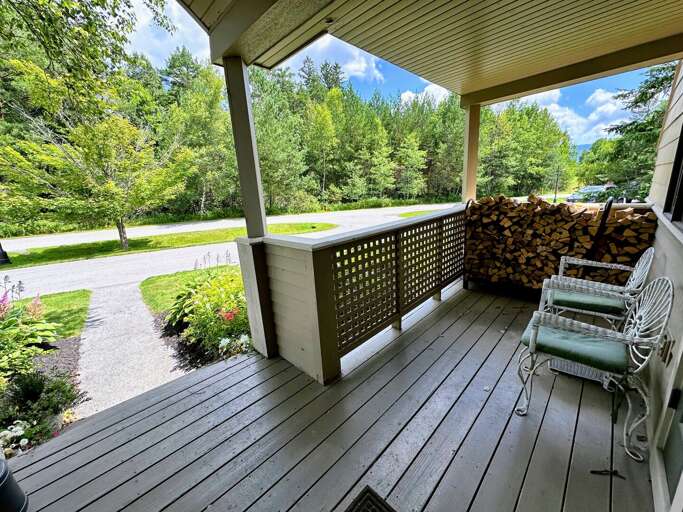Veranda View With Vibrant Greenery, Picturesque Peaks, And Piled Logs At A Vacation Rental