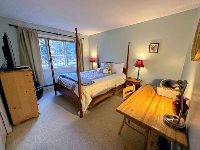 Queen bedroom with desk and TV.