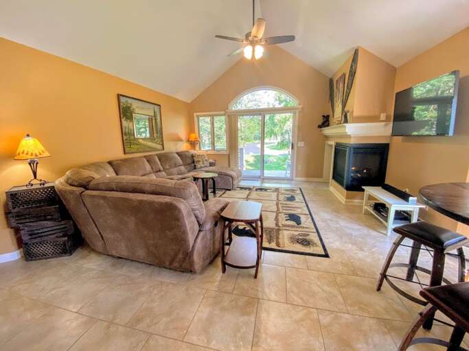 The dining/living area has a sunny open concept space with rustic dining table that seats 4 and comfortable furniture that surrounds the gas fireplace.