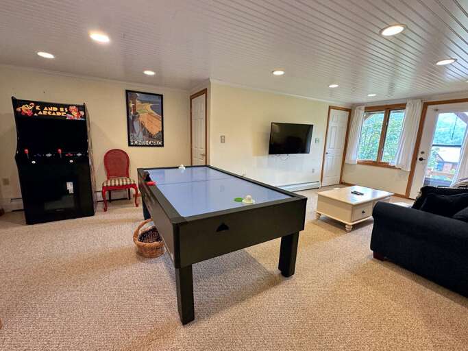 Lower level living area with TV, air hockey, and arcade console