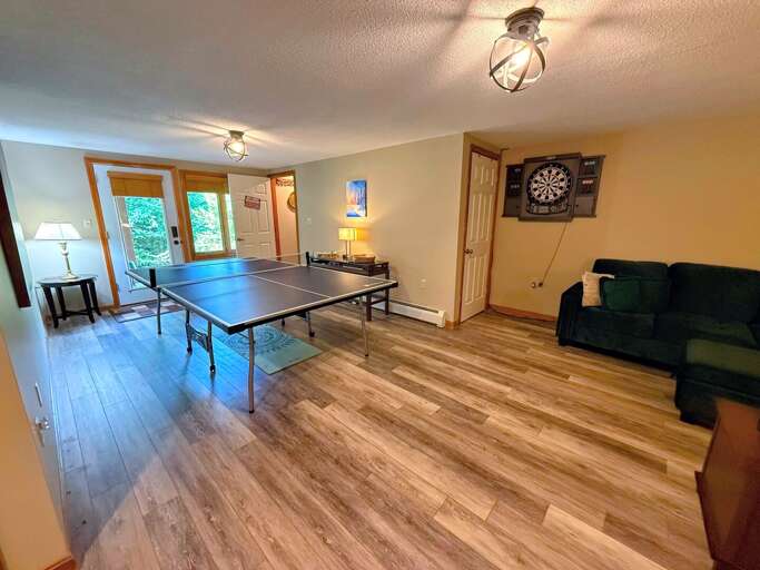 Spacious Room With Ping Pong Table, Plush Sofa, And Wooden Floors Flanking French Doors