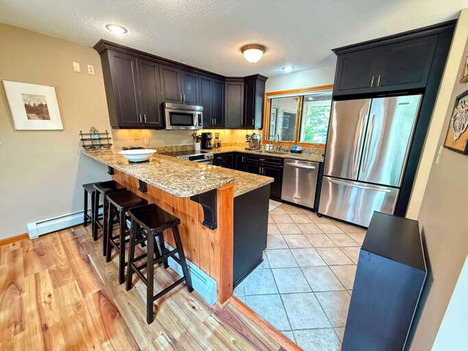 The renovated kitchen features high-end stainless steel appliances, granite countertops, and a spacious breakfast bar with seating for 4 —perfect for preparing meals and gathering with loved ones. The renovated kitchen features high-end stainless steel appliances, granite countertops, and a spacious breakfast bar with seating for 4 —perfect for preparing meals and gathering with loved ones.