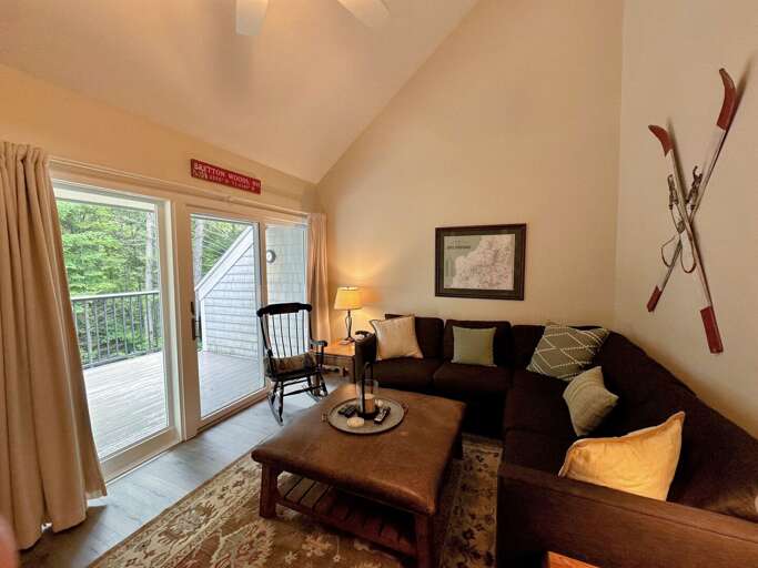 Main level living room with TV, gas fireplace, and walkout to deck
