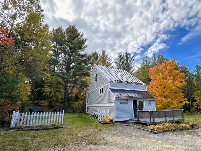 White House With Fence Surrounded By Autumn Trees And Blue Sky