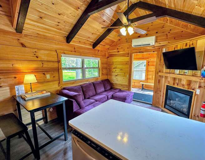 Living room with TV, fireplace and dining area with stools