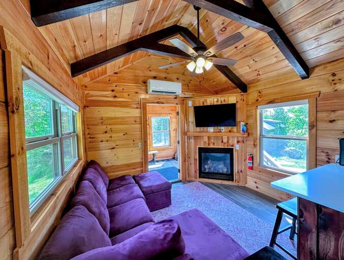 The main living space has a couch, TV, and gas fireplace with a table.