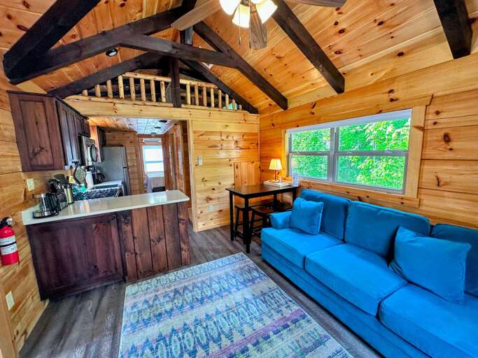 The main living space has a couch with pull-out bed, TV and gas fireplace with a table and barstool seating adjacent to the kitchen.