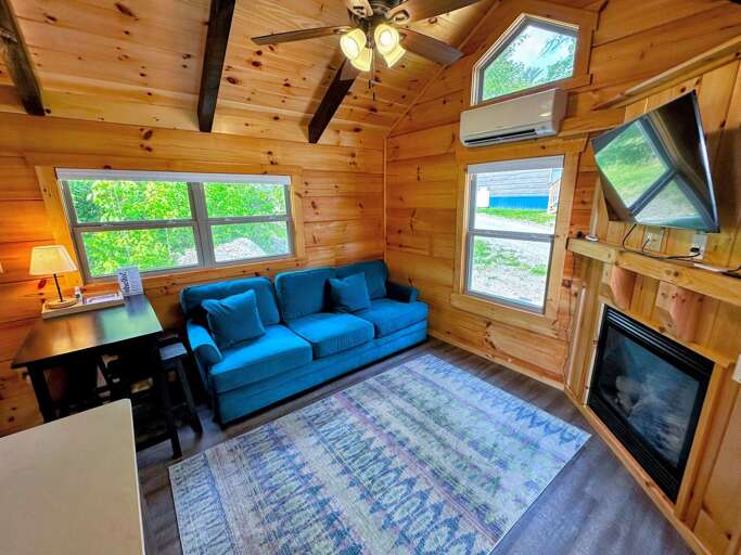 The main living space has a couch with pull-out bed, TV and gas fireplace with a table and barstool seating adjacent to the kitchen.
