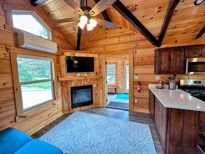 The main living space has a couch with pull-out bed, TV and gas fireplace with a table and barstool seating adjacent to the kitchen. The main living space has a couch with pull-out bed, TV and gas fireplace with a table and barstool seating adjacent to the kitchen.