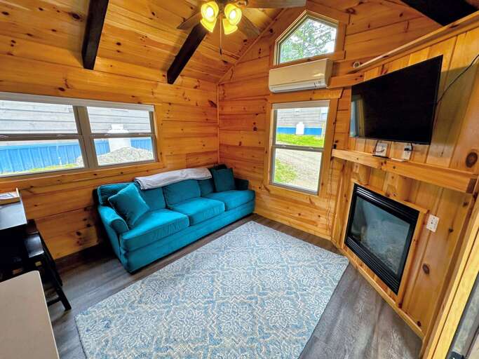 The main living space has a couch with pull-out bed, TV and gas fireplace with a table and barstool seating adjacent to the kitchen. The main living space has a couch with pull-out bed, TV and gas fireplace with a table and barstool seating adjacent to the kitchen.