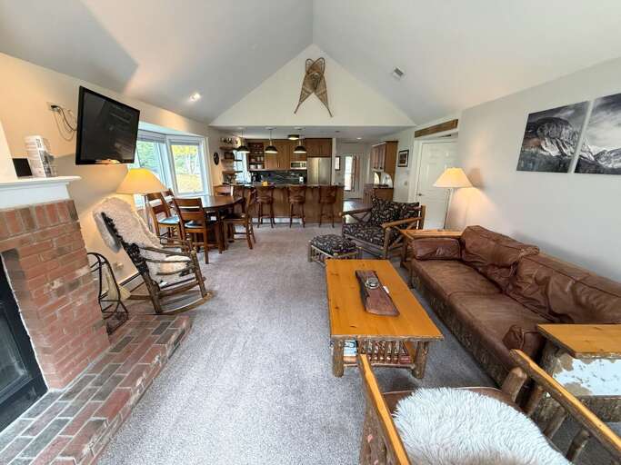 The open living area connects comfortable sofa and armchair seating with the dining space and kitchen breakfast bar.