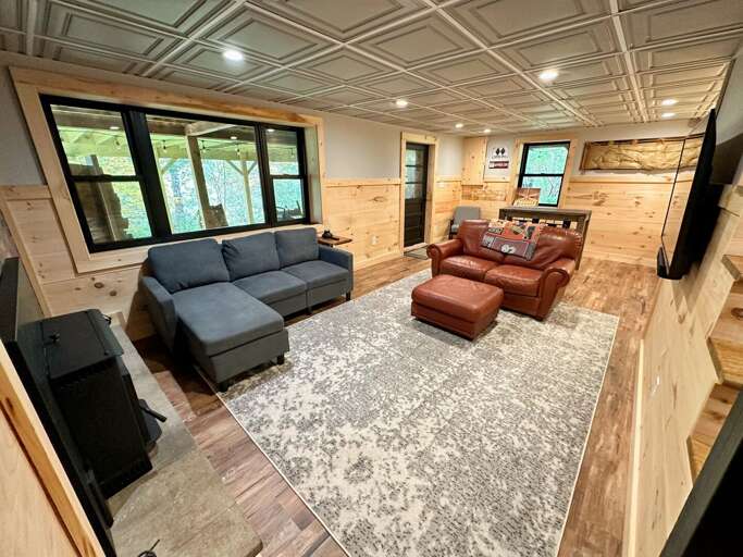 Lower level living space with pellet stove, TV, dry bar, and lower exit.