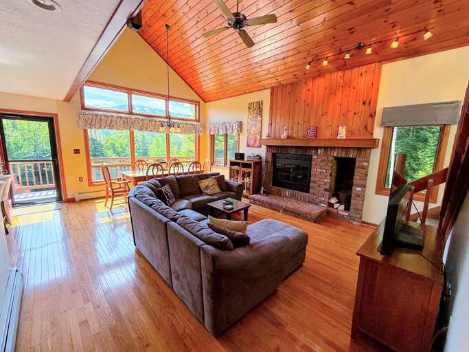 Open living area with sectional sofa, fireplace and TV adjacent to Kitchen and Dining areas