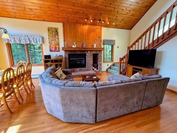 Open living area with sectional sofa, fireplace and TV adjacent to Kitchen and Dining areas