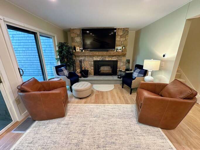 Main level living area with comfortable seating, TV, wood burning fireplace, and walkout deck