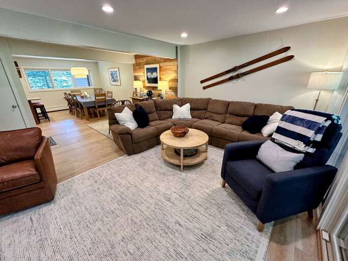 Main level living area with comfortable seating, TV, wood burning fireplace, and walkout deck