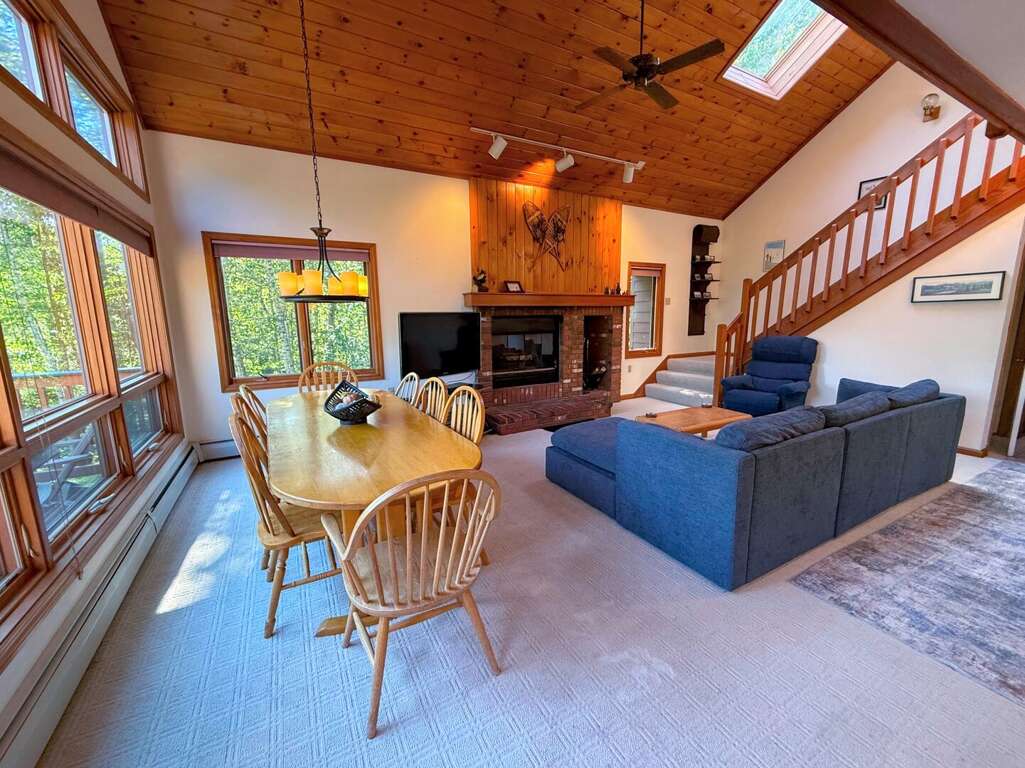 Main level dining and living area with wood fireplace, TV with cable, and walkout to main level deck. Main level dining and living area with wood fireplace, TV with cable, and walkout to main level deck.