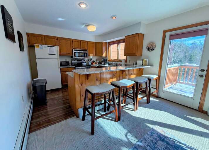Main level kitchen area with granite countertop and 4 barstools. Main level kitchen area with granite countertop and 4 barstools.