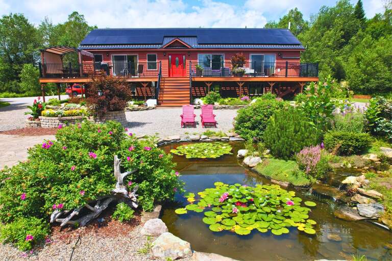 Moose Lodge, the largest of the three homes, features 5 bedrooms, 3 bathrooms, AC, hot tub, and fire pit. Enjoy a beautiful outdoor space with a pond and outdoor kitchen for the perfect retreat.