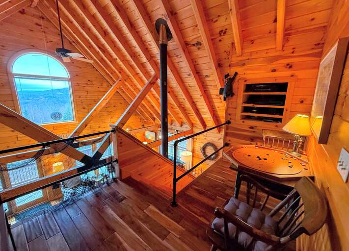 The upper-level has a sitting area with a game table and a bookshelf with games, movies, and books for entertainment The upper-level has a sitting area with a game table and a bookshelf with games, movies, and books for entertainment