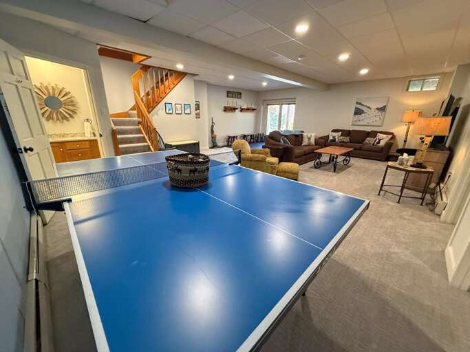 A second gathering space downstairs offers comfortable seating, a TV, a ping pong table, and walkout access to the parking area.