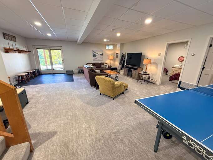 A second gathering space downstairs offers comfortable seating, a TV, a ping pong table, and walkout access to the parking area.
