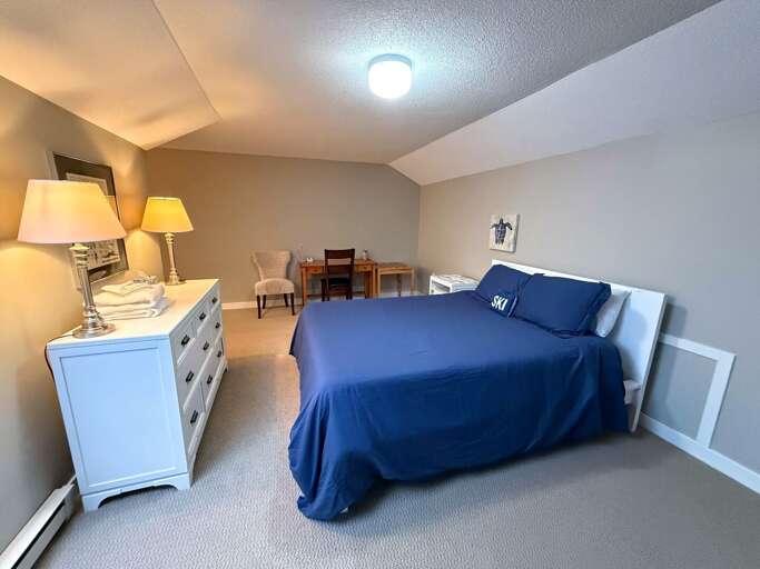 The loft sleeping area has a queen bed, dresser, and a small desk beneath the sloped ceiling.